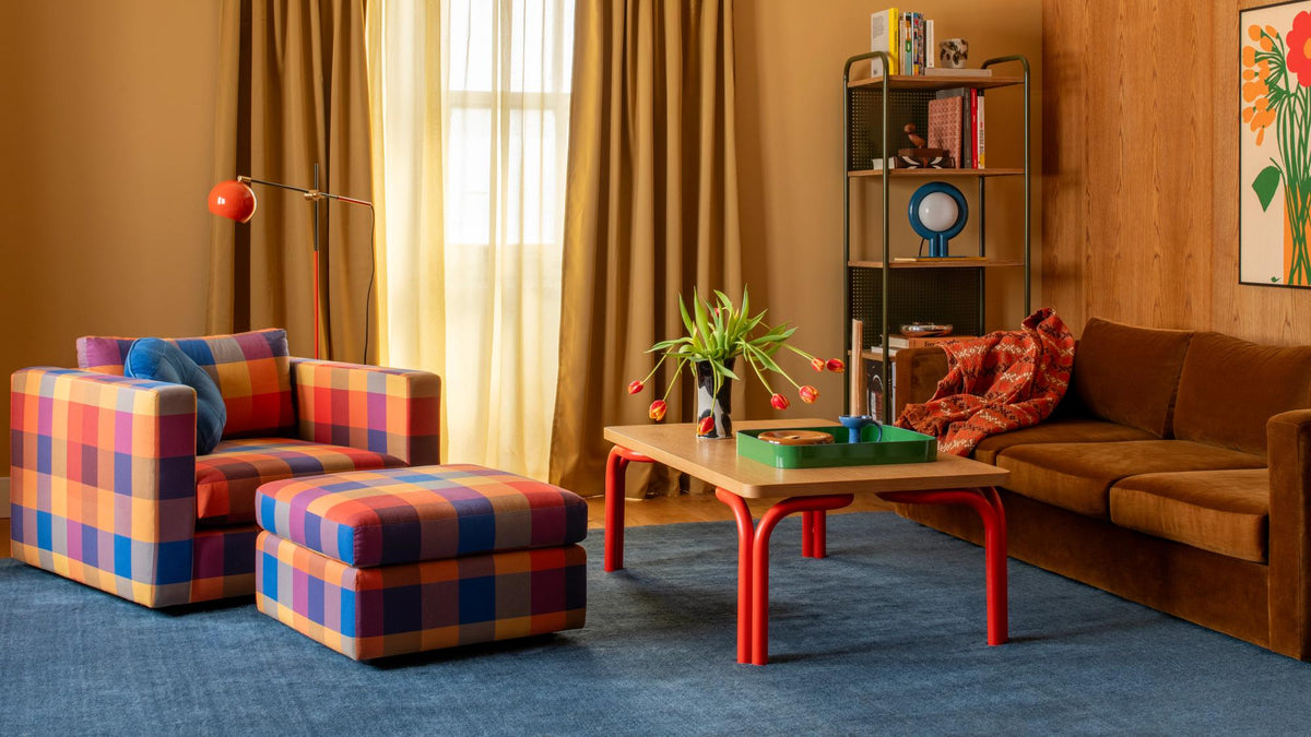 Colorblock plaid armchair and ottoman in a warm wood-paneled living room