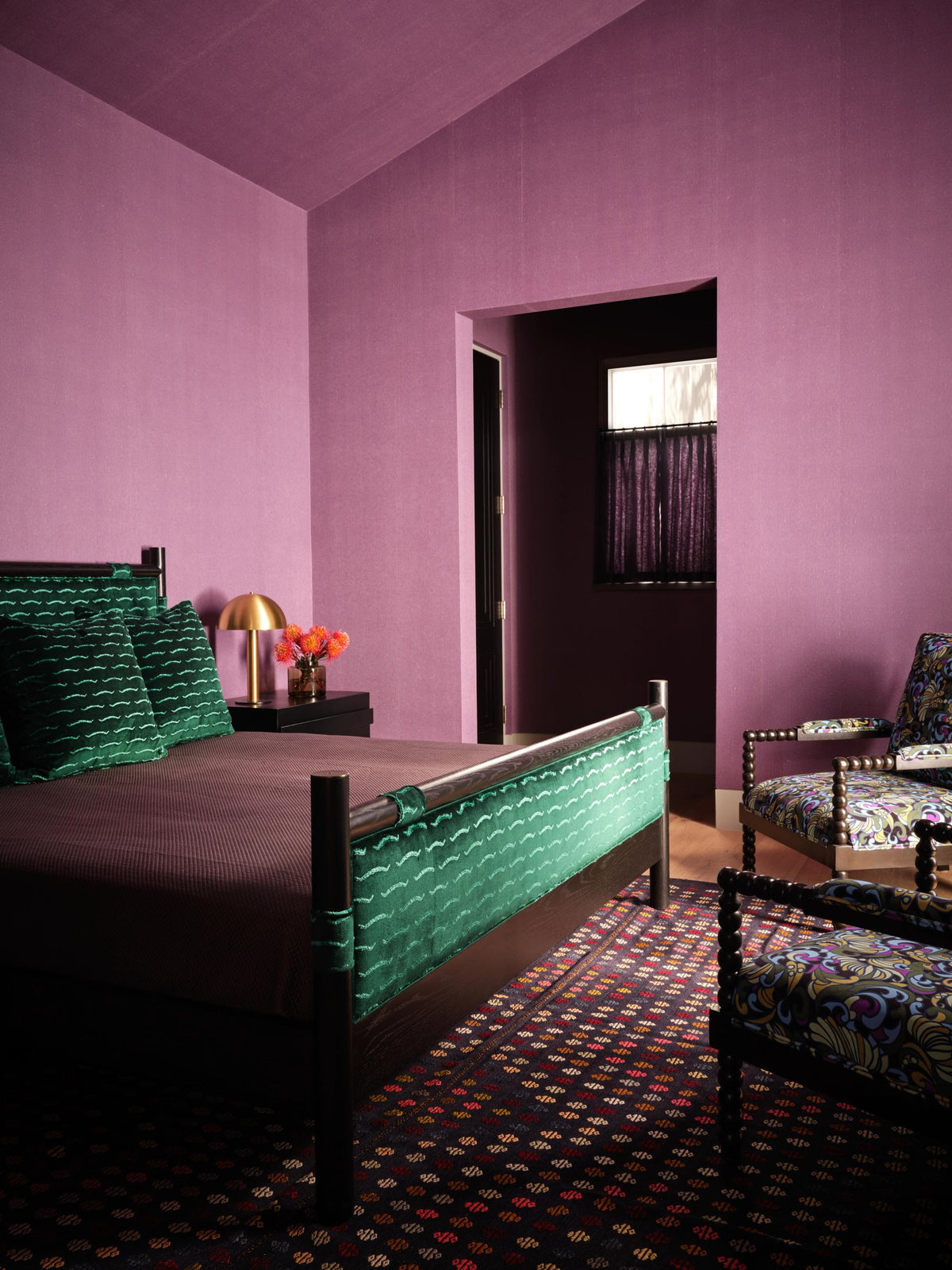Colorful bedroom featuring a green patterned bed, patterned armchair, and purple walls