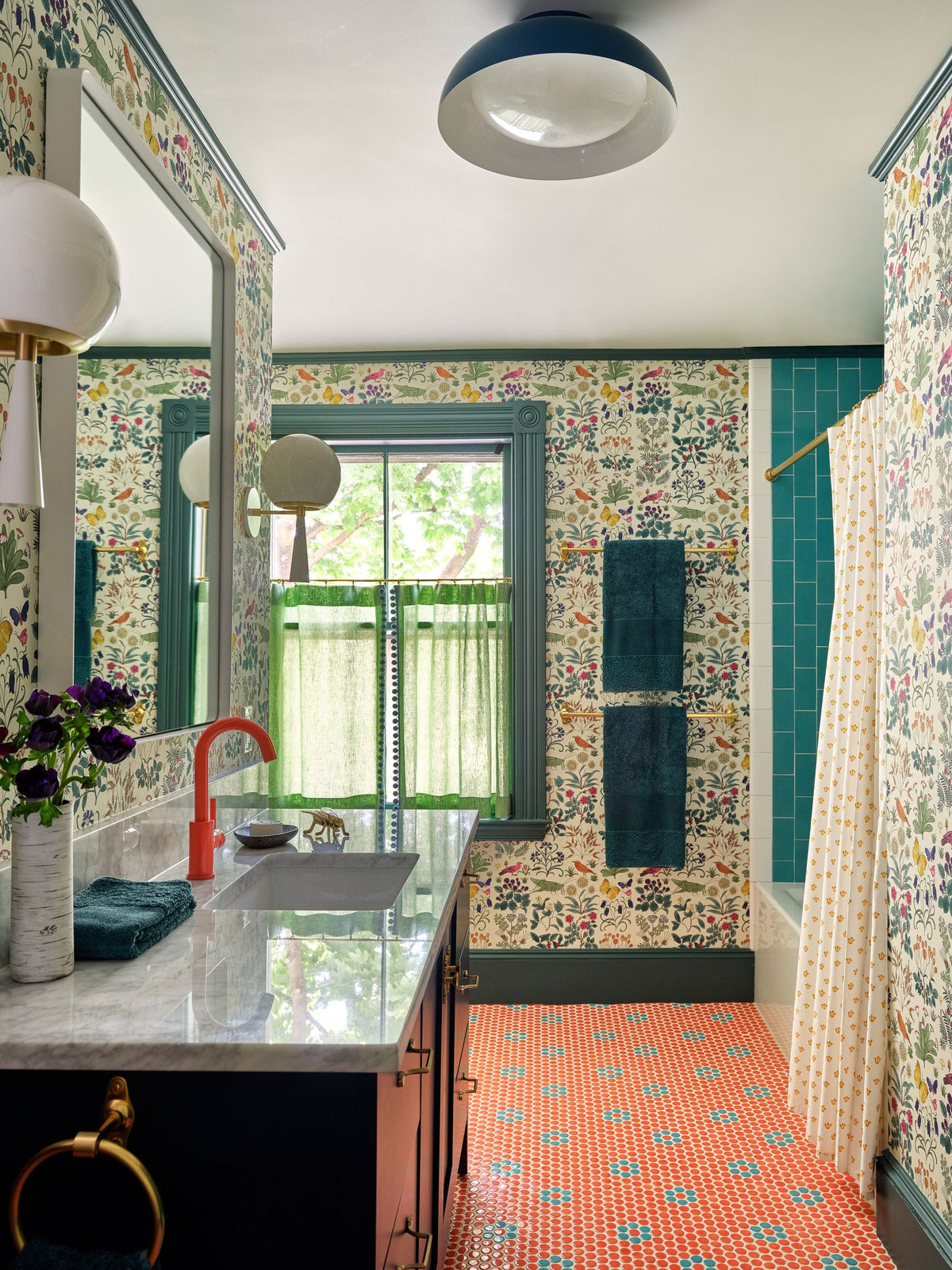 Colorful bathroom with floral wallpaper, teal trim, marble vanity, green curtains, and patterned tile floor