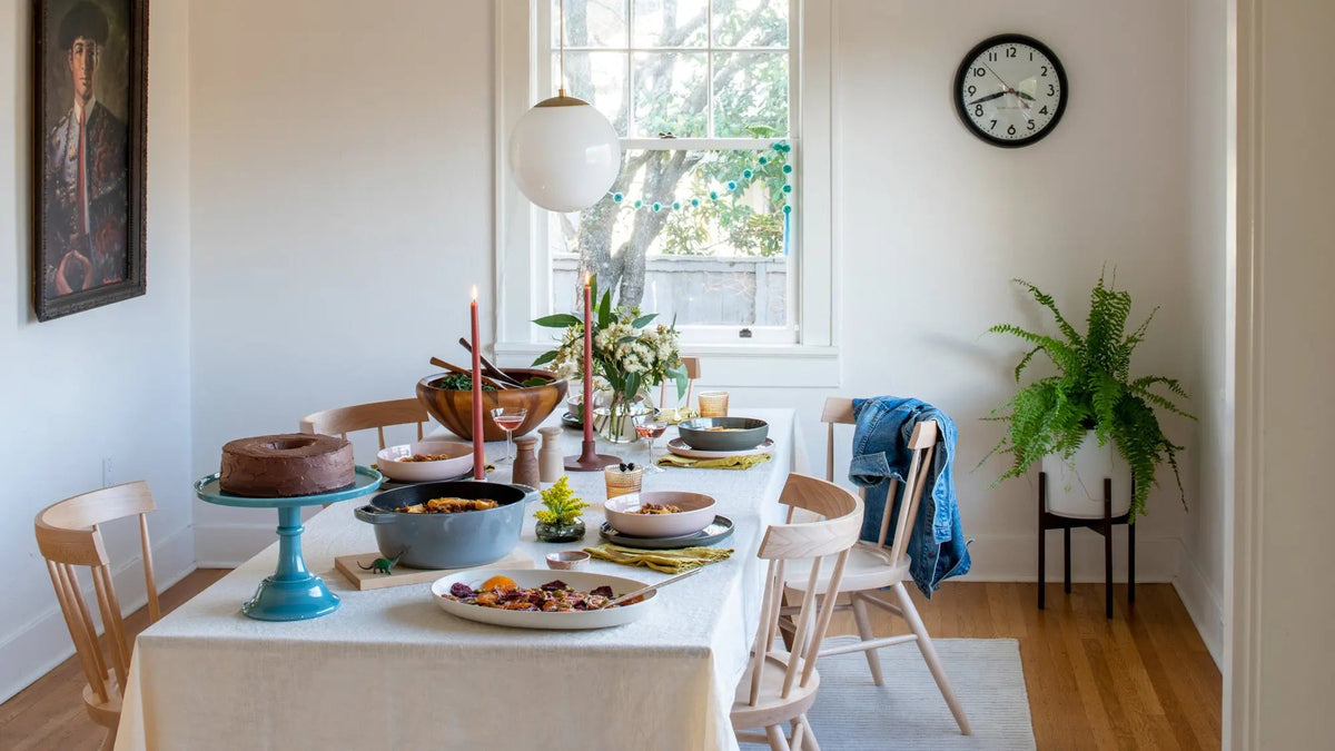 Dining room set for a meal with a decorated table, pendant light, and potted fern