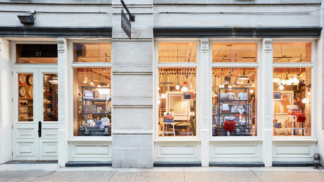 Exterior of Schoolhouse New York storefront with warm-lit window displays of light fixtures, shelving, and homewares in Tribeca