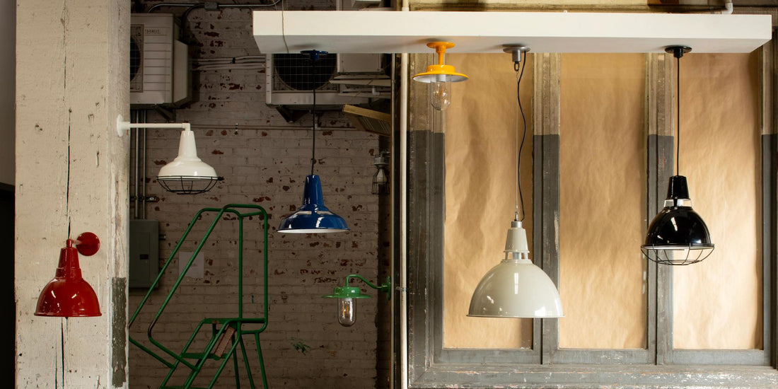 Colorful pendant lights displayed in an industrial factory showroom with exposed brick and wood walls
