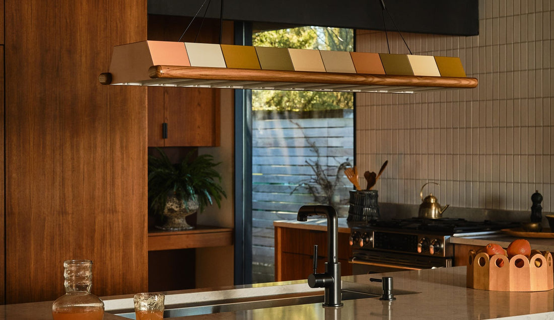 Low-lit kitchen island with metal multi-colored chandelier over deep metal sink