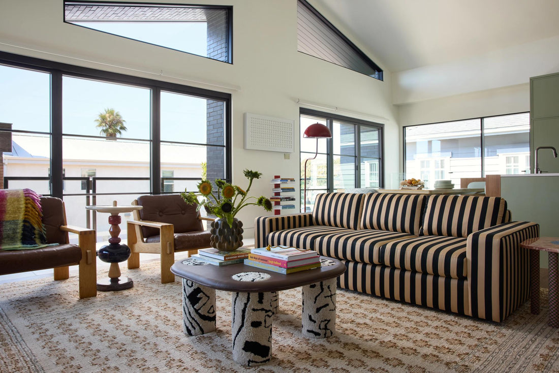 Living room with striped sofa, view of palm tree outside.
