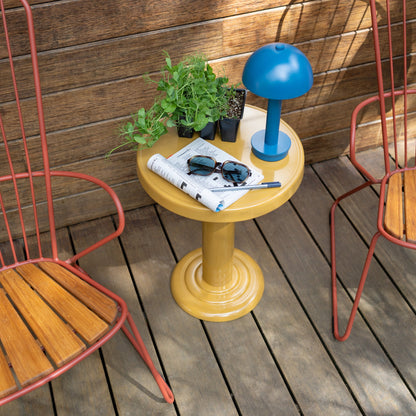 Top view of Owen Side Table showing mustard yellow gloss pedestal, blue lamp and potted seedlings on a wooden deck