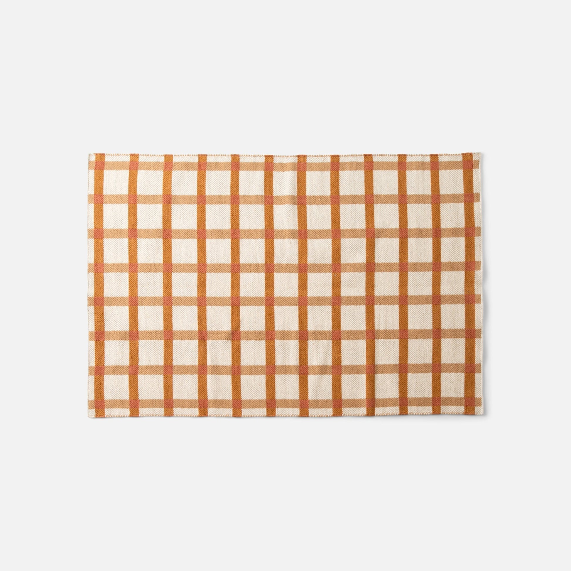 Overhead view of Plaid Wool Reversible Rug showcasing orange and cream high-contrast plaid, handwoven natural-dyed wool on white background