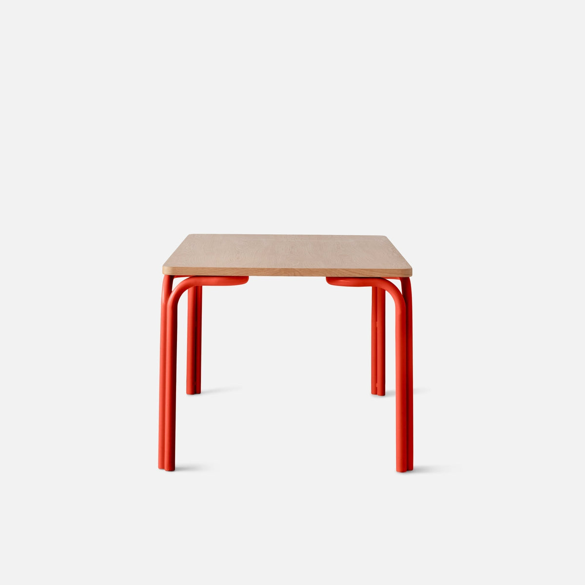 Front view of Forma Dining Table showcasing a light oak veneer top and red powder-coated steel legs with a white background