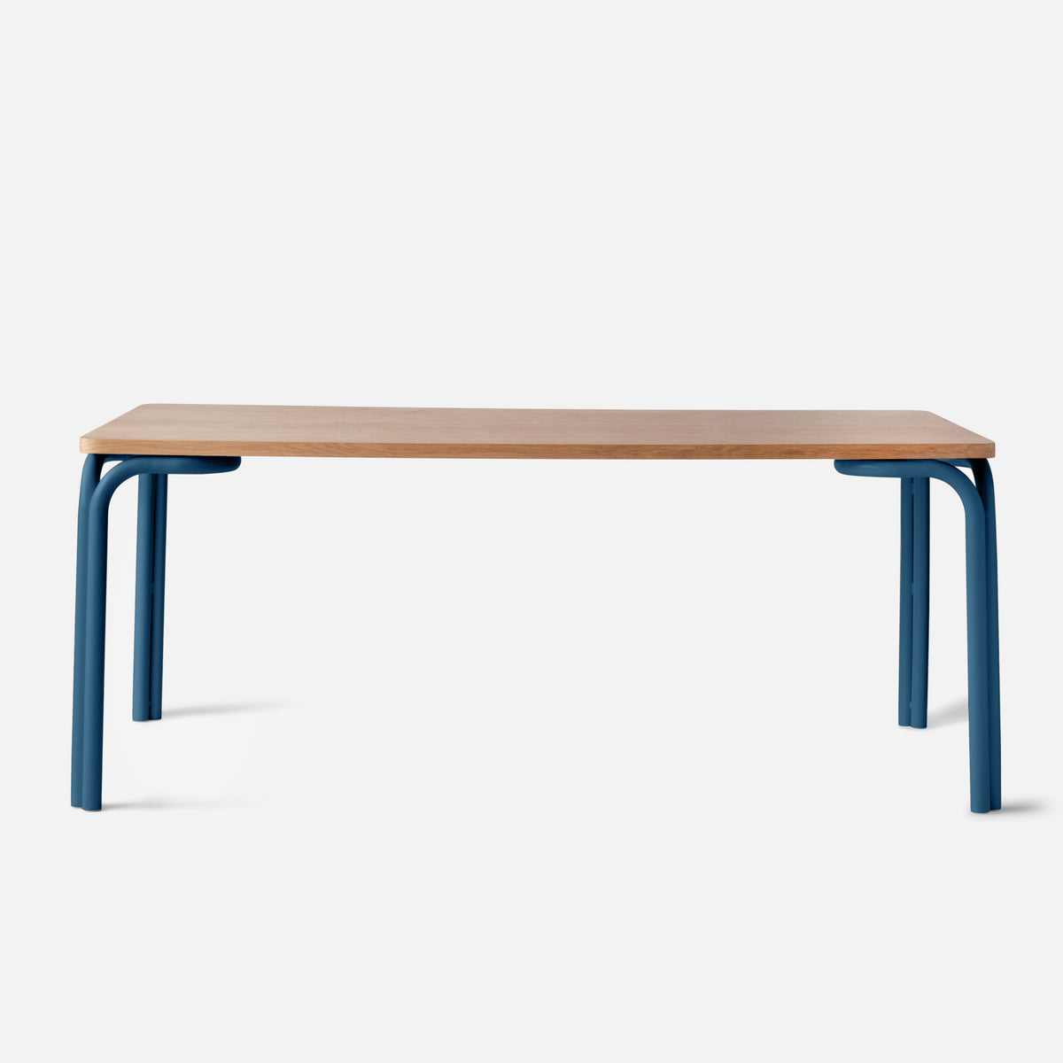 Front view of Forma Dining Table showcasing oak veneer top and blue powder-coated steel legs with a white background