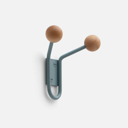 Close-up of Mollie Double Hook showing two oak ball hooks on lichen painted steel mounting against a white wall