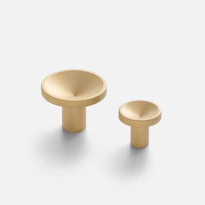 Angled view of Rhone Knob in cast brass showcasing recessed textured faces and two sizes on a light background