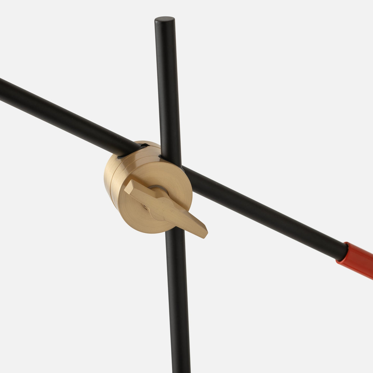 Close-up of Isaac Desk Lamp showcasing brass swivel joint and adjustable steel arm against a light gray background