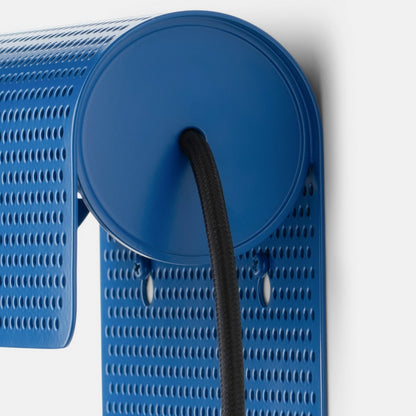 Close-up view of the Swell Plug-In Sconce in cobalt-satin showing its perforated steel shade and black cord