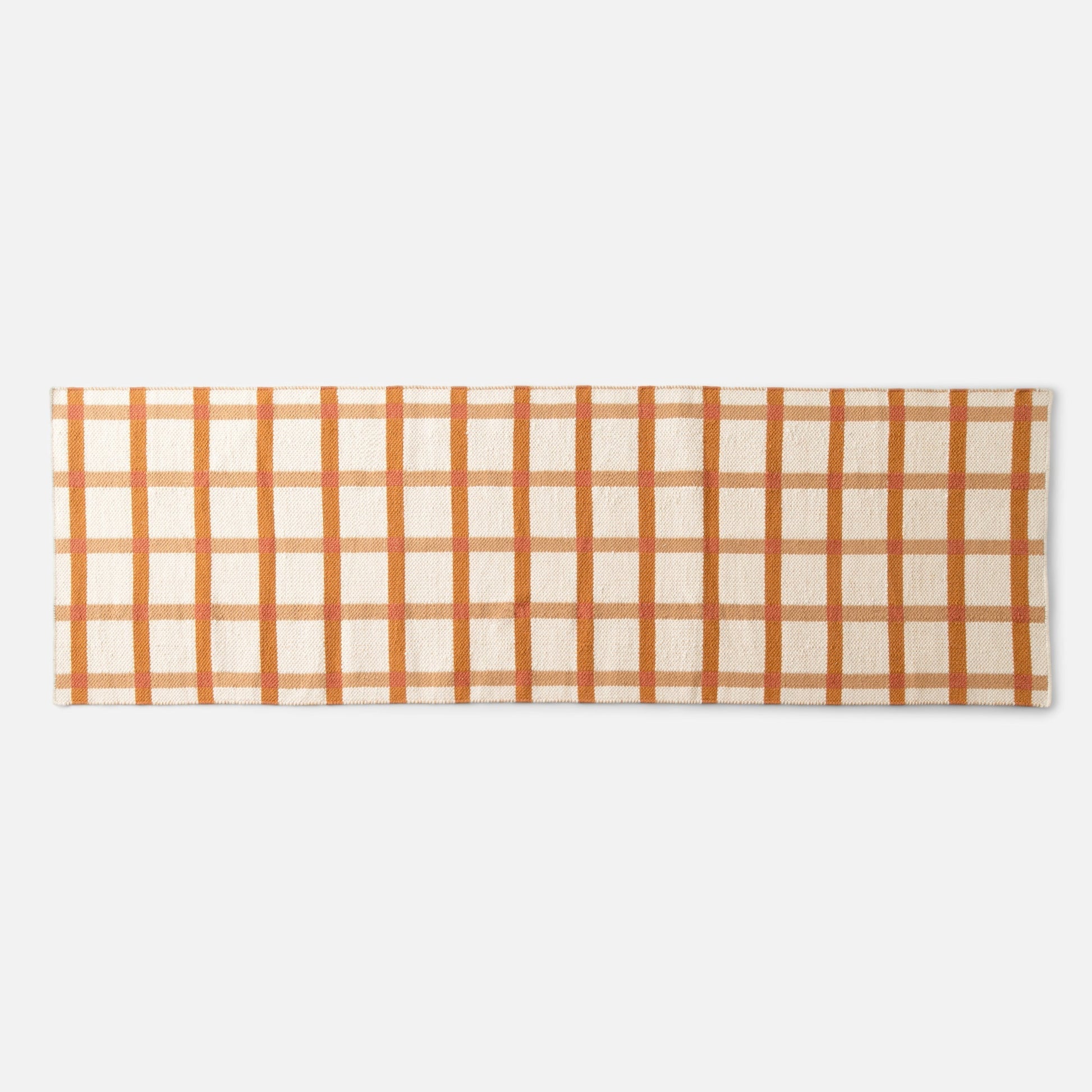 Top-down view of Plaid Wool Reversible Rug showcasing orange-and-beige plaid and handwoven wool texture on a white background