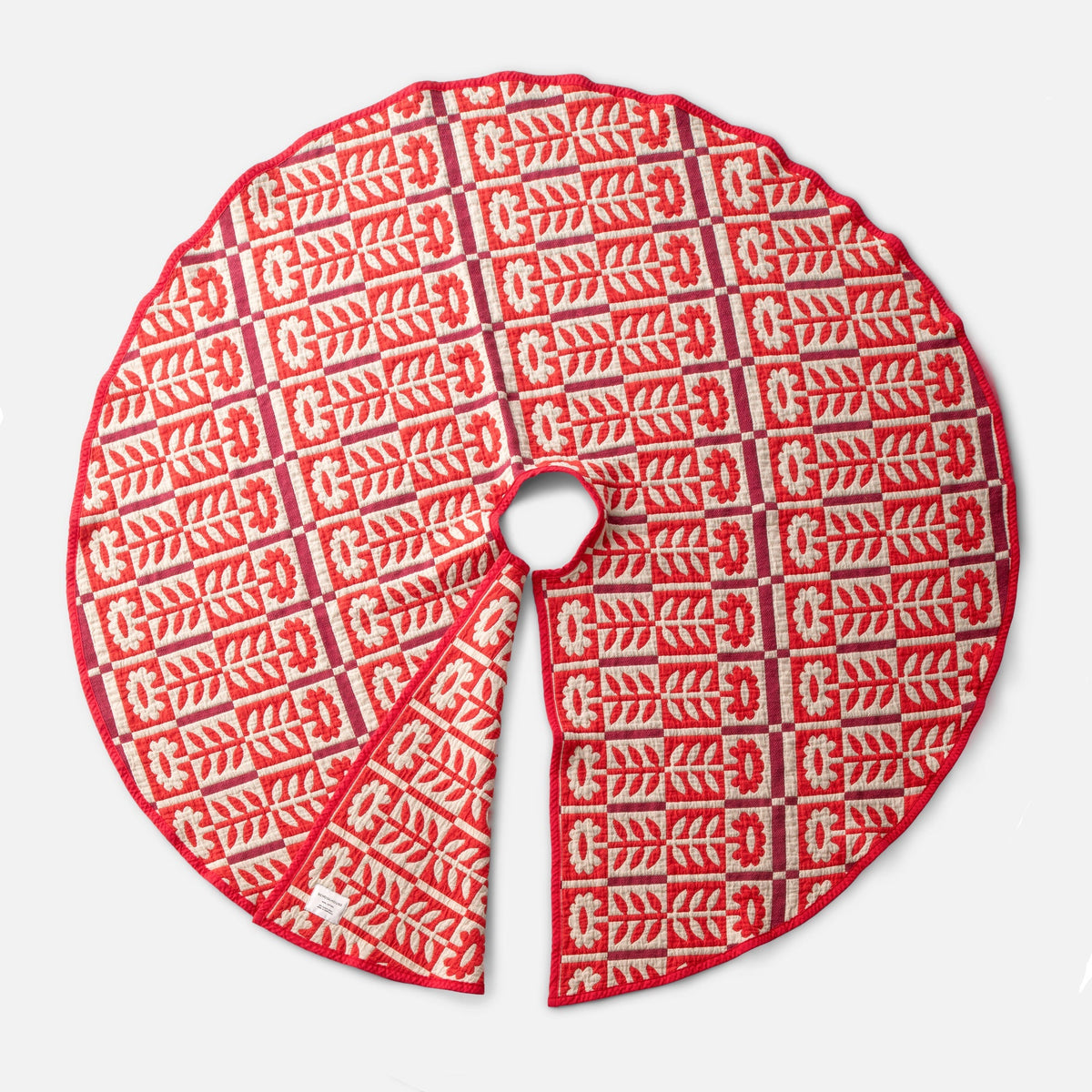 Top view of red Stillwater Tree Skirt showcasing a floral quilt pattern and center opening on a white background