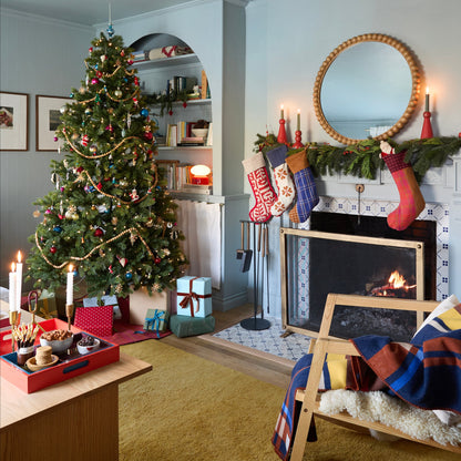 Stillwater Stocking hanging on a garland-draped fireplace mantel in a festive living room