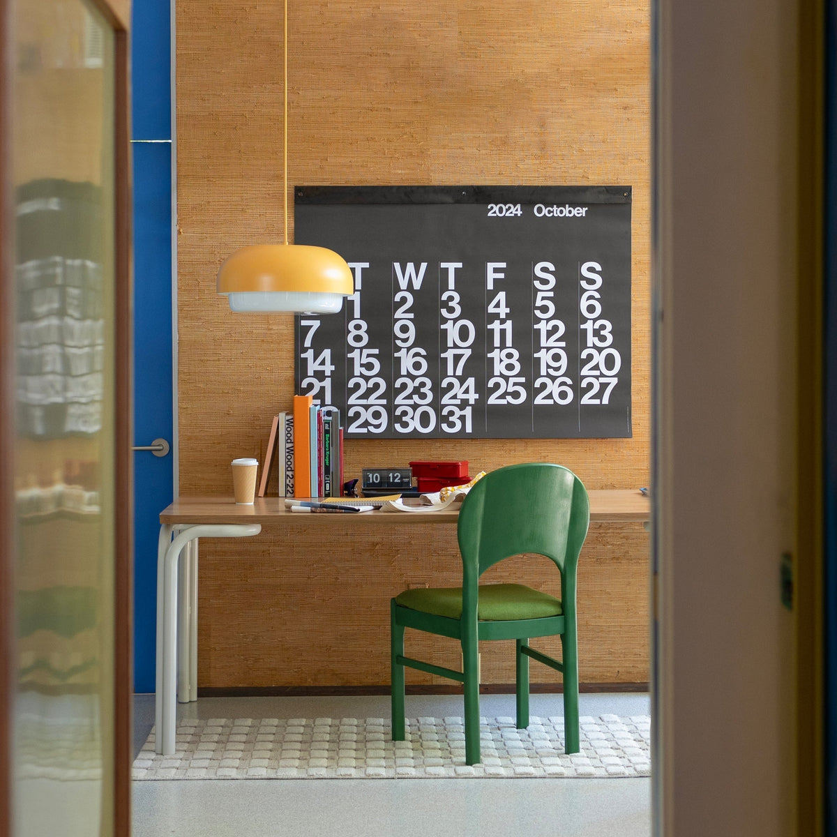 Front view of Forma Dining Table showcasing its wooden top and steel legs with a home office background