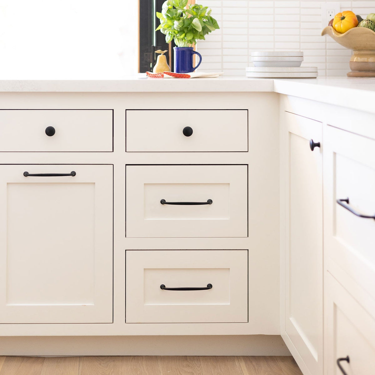 Black Somerset knobs installed on white kitchen cabinets in a bright kitchen