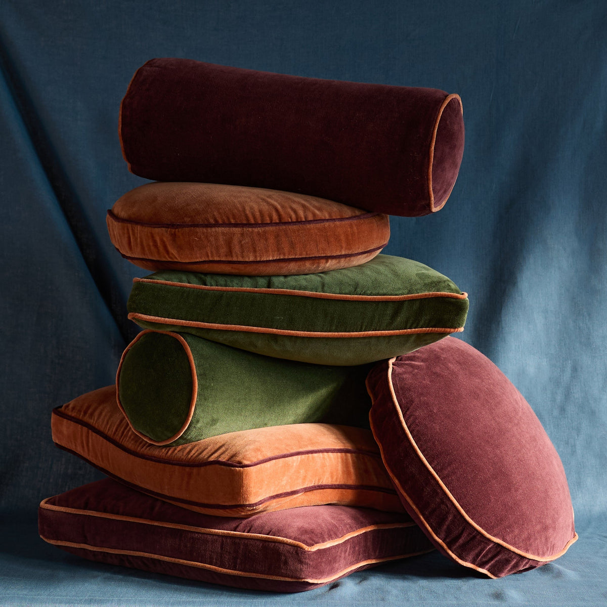 Stacked view of the Velvet Piped Pillow showcasing soft cotton velvet and contrast piping against a blue backdrop