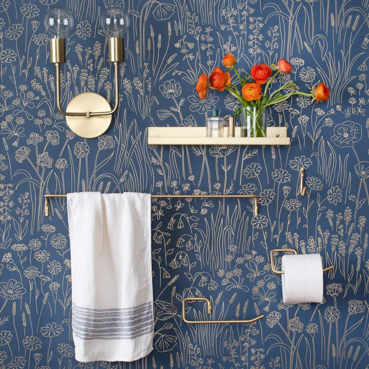 Front view of Mara Towel Holder showcasing its brass bar holding a white towel against floral wallpaper