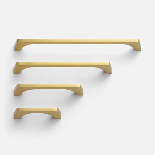 Top-down view of four Truss Pull cabinet pulls in satin brass, staggered sizes showing angled edges and rectangular profile on light gray background