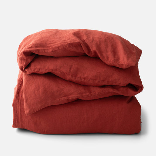 Folded linen duvet cover showing paprika red textured linen and relaxed wrinkles on white background