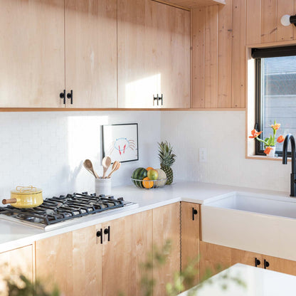 Pair of matte black Galley Pulls installed on light wood kitchen cabinets with white tile backsplash