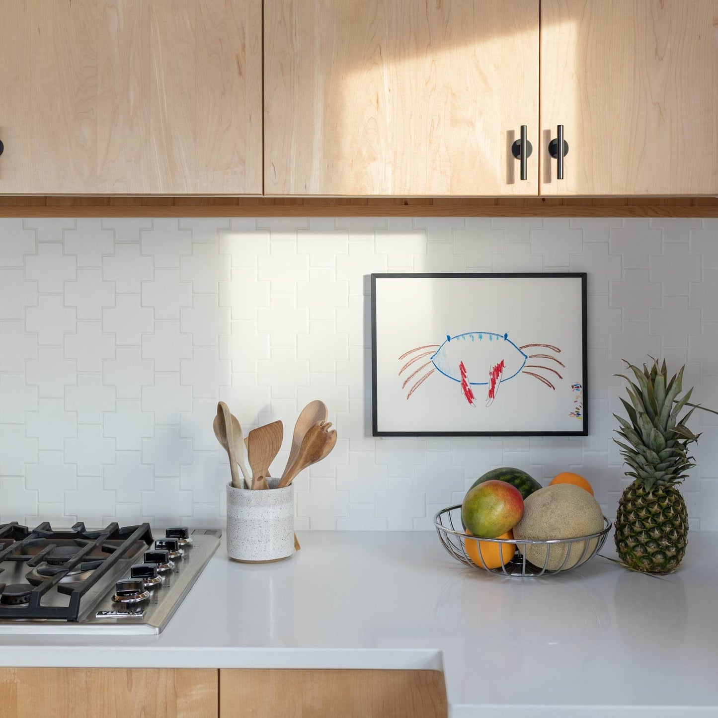 Two matte black Galley Pulls mounted on light maple cabinet doors above a white tiled backsplash in a bright kitchen