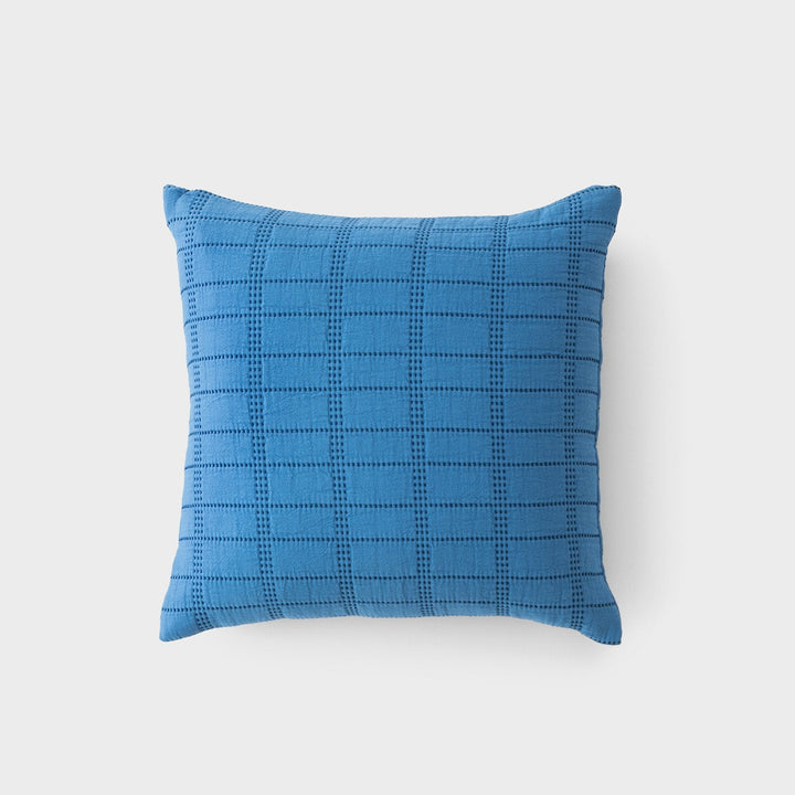 Top-down view of Grid Stitch pillow showcasing blue knit grid stitch pattern on light gray background