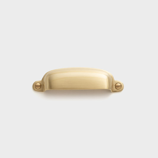 Front view of Brunswick cup pull showcasing aged brass finish and exposed screw mounts on light gray background