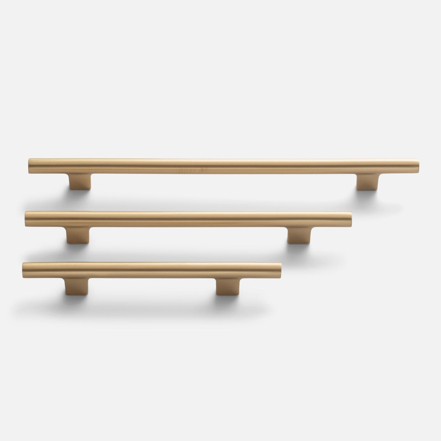Front view of three Galley Pulls in natural brass showcasing smooth rounded bar profile and T-shaped supports on a white background