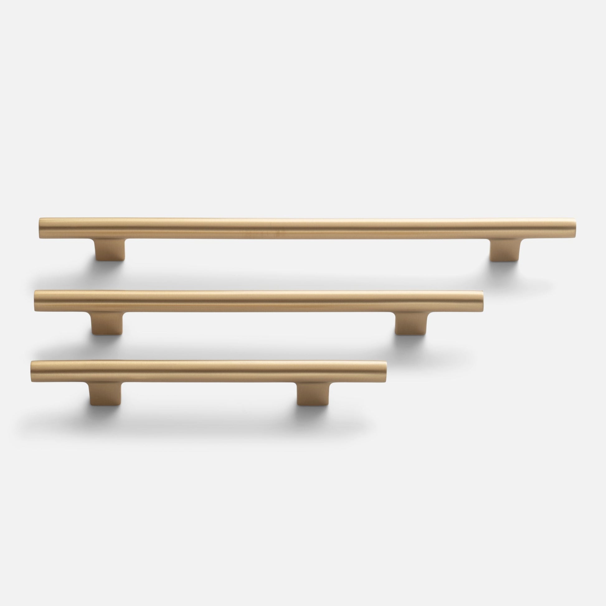 Front view of three Galley Pulls in natural brass showcasing smooth rounded bar profile and T-shaped supports on a white background